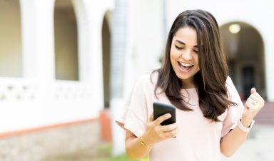Woman Receiving Good News On Smartphone Outdoors DFEI