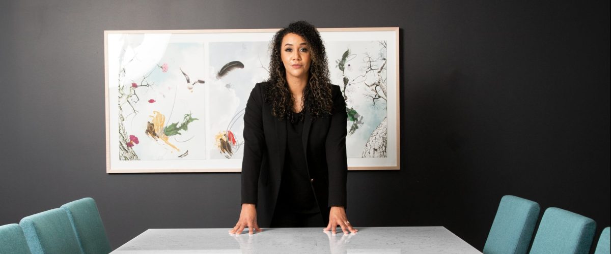 Danielle Shoots a lightskin black woman standing in a conference room with her hands on the table and her face facing the horizon.