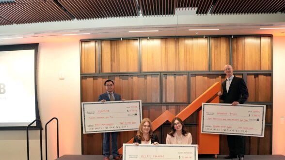 Three winning student teams pose on stage holding large award checks at THE CLIMB Pitch Night, celebrating their placements.