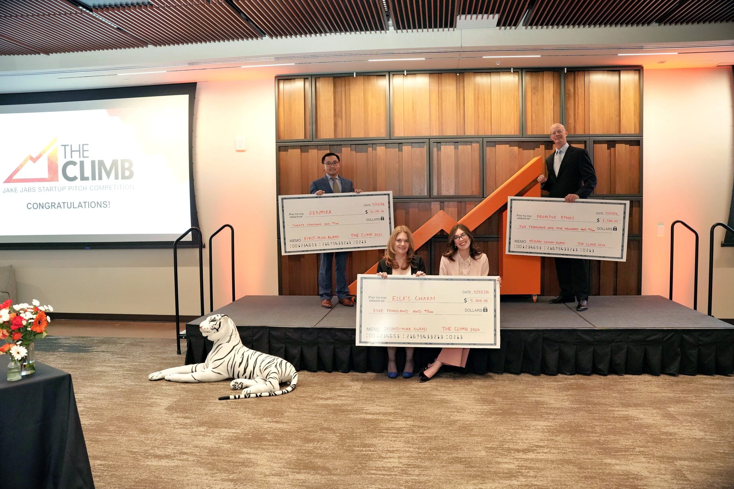 Three winning student teams pose on stage holding large award checks at THE CLIMB Pitch Night, celebrating their placements.