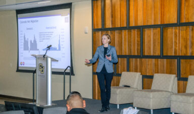 colorado state demographer kate watkins standing in a conference as she's making a presentation